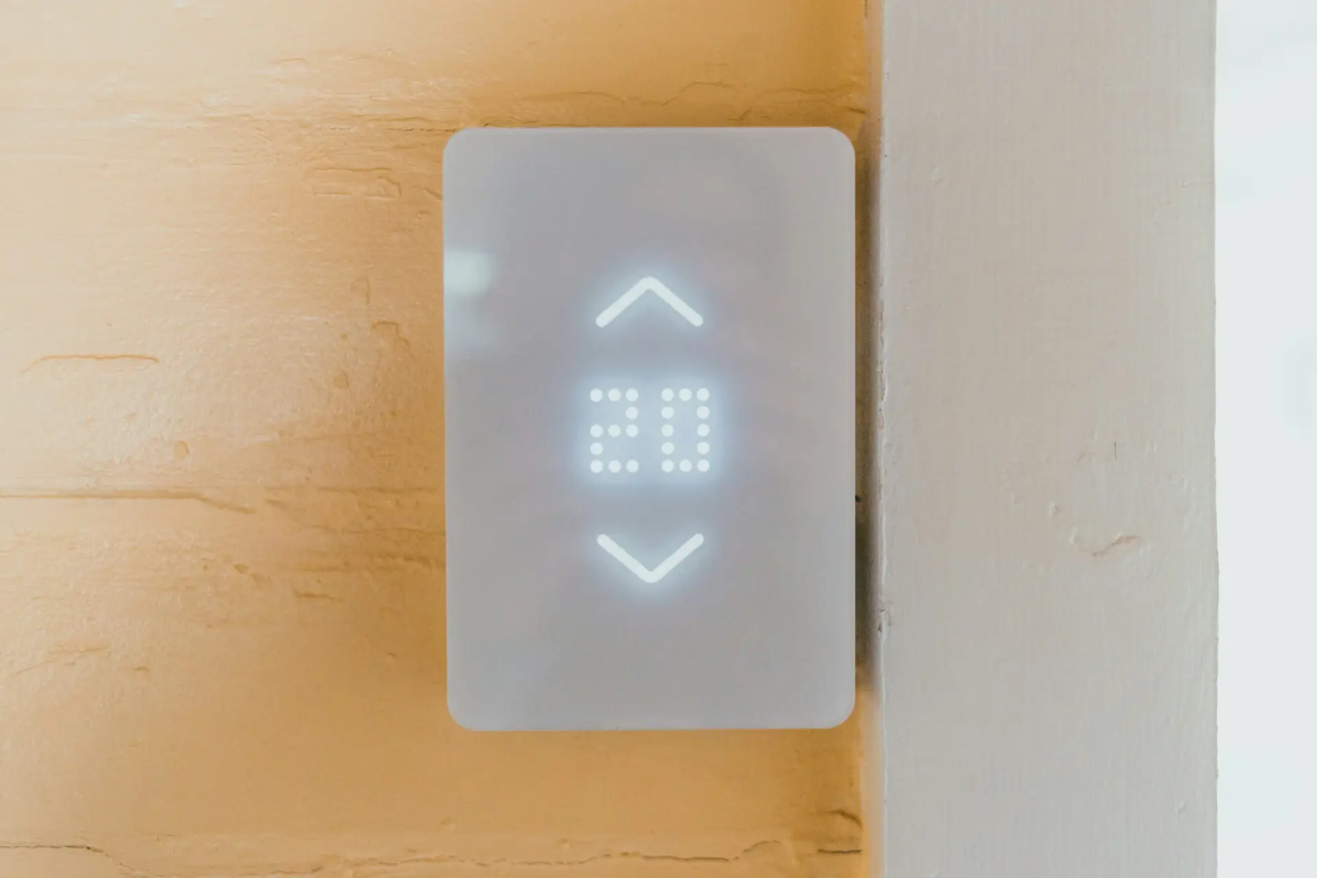 Modern, falra szerelt érintőkijelzős termosztát világító digitális kijelzővel, amely az aktuális szobahőmérsékletet és a fűtési módot mutatja.