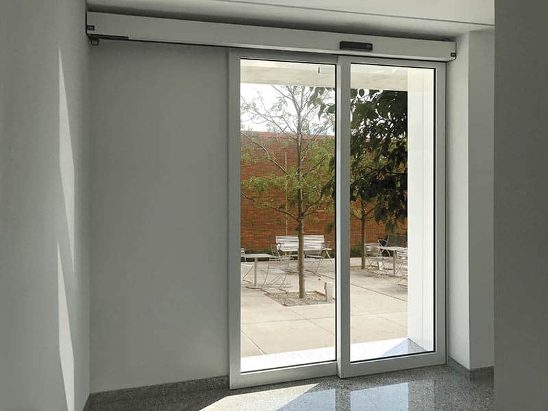 Ditec DAS típusú automata toló üvegajtó egyedi portálszerkezetbe integrálva, biztonsági érzékelőkkel és digitális programkapcsolóval, a TEMA által telepítve.