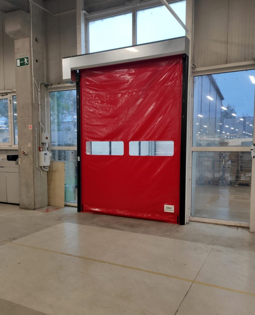 Ditec Soft Reset típusú, rugalmas alsó éllel ellátott beltéri PVC gyorskapu, átlátszó szekcióval és integrált motorral, a TEMA által telepítve.