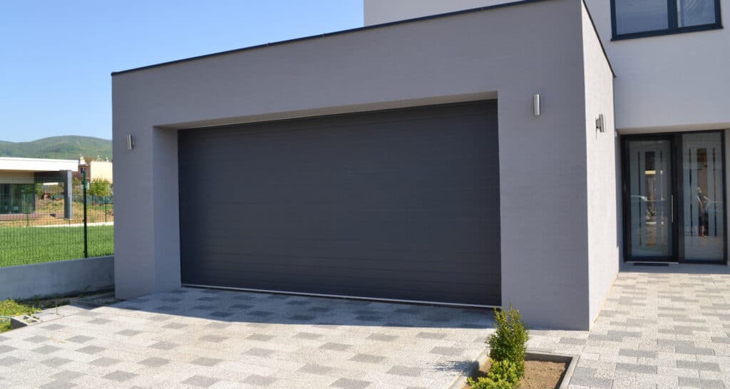 Modern, antracit színű Ditec szekcionált garázskapu hőszigetelt panelekkel, szakszerű TEMA telepítéssel és integrált motoros mozgatással.